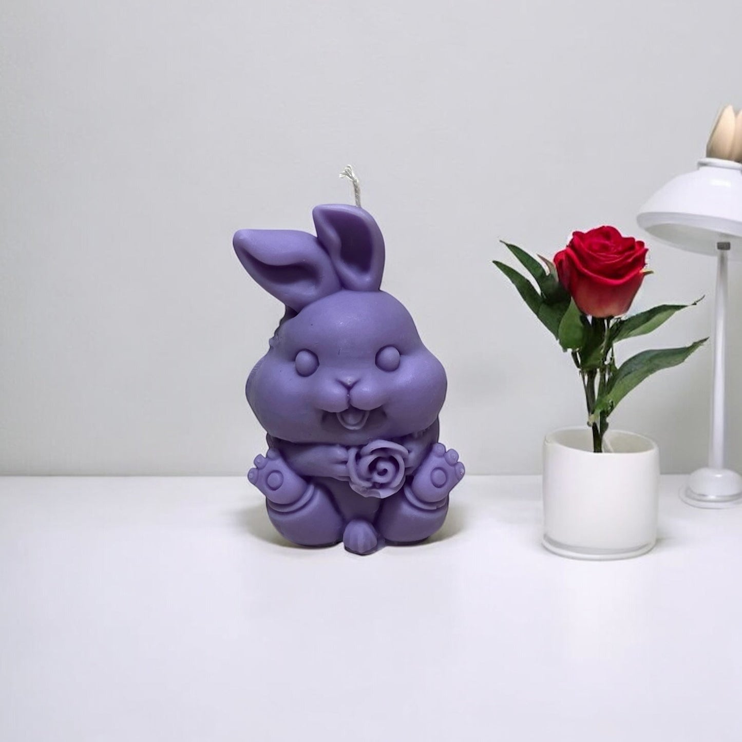 Candela decorativa profumata a forma di coniglietto lilla, realizzata a mano in cera vegetale da Essenza di Luce.