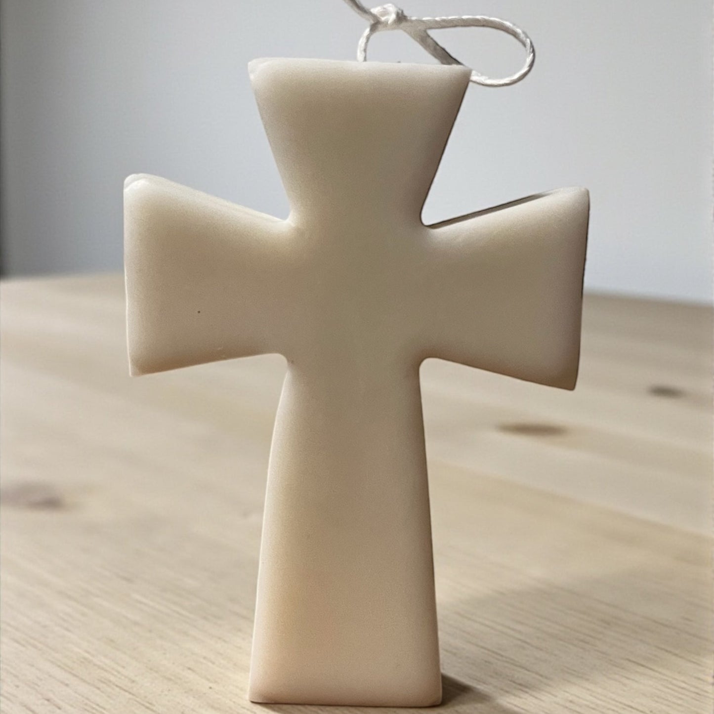 Candela decorativa a forma di croce in cera chiara, realizzata artigianalmente, simbolo di fede e spiritualità.