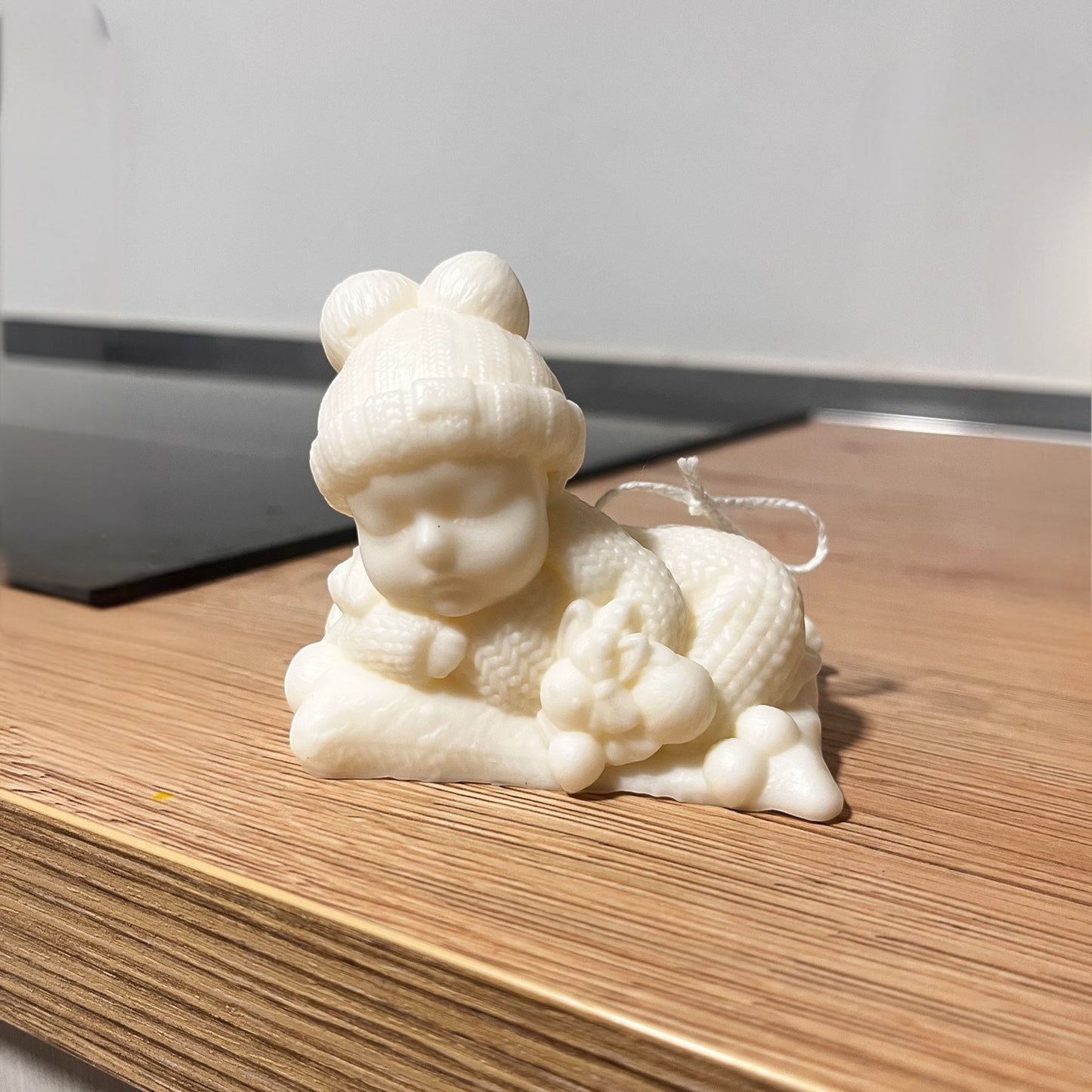 Candela decorativa a forma di bebè in cera chiara, realizzata artigianalmente, ideale come bomboniera nascita o battesimo.