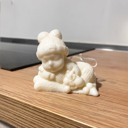 Candela decorativa a forma di bebè in cera chiara, realizzata artigianalmente, ideale come bomboniera nascita o battesimo.