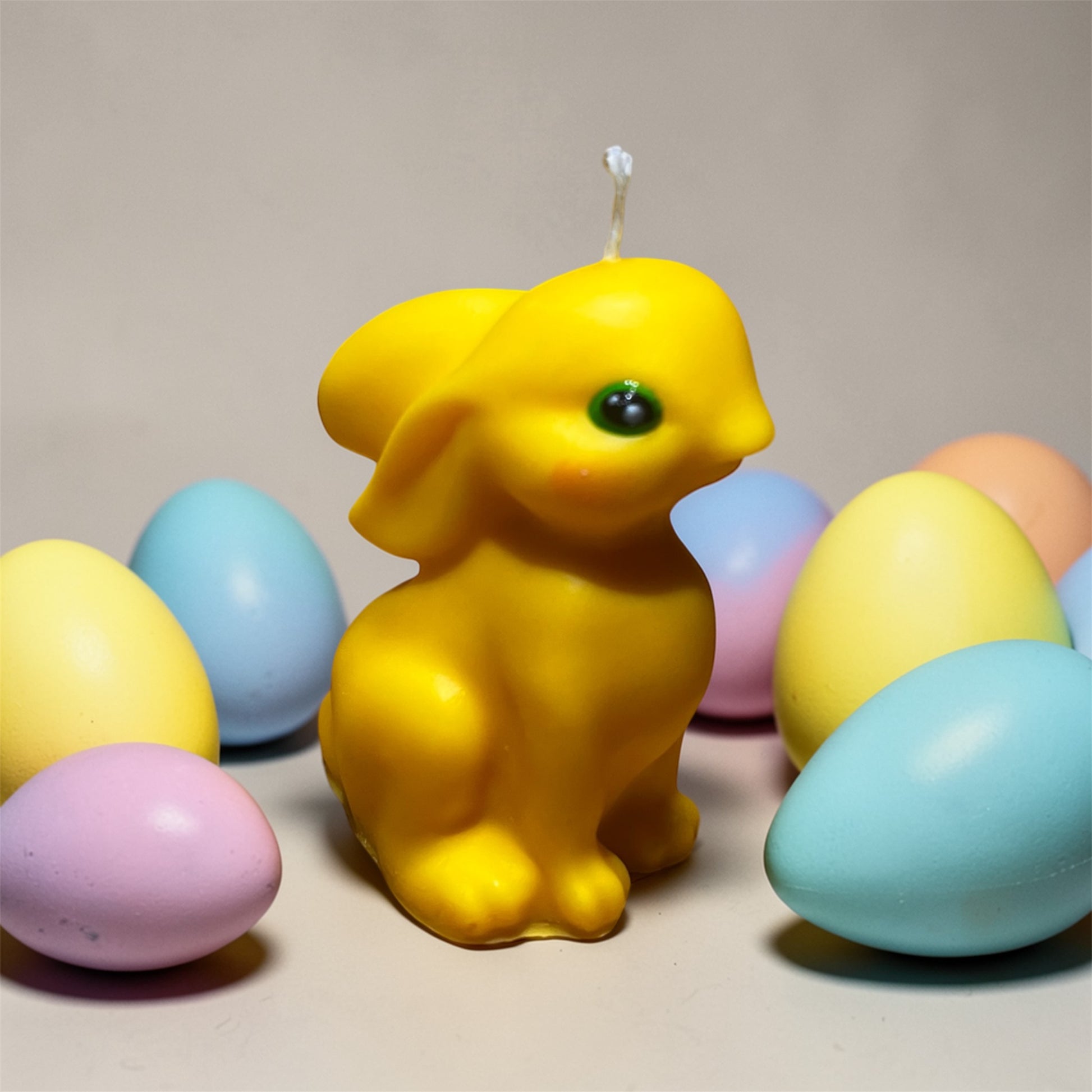 Candela decorativa coniglietto pasquale giallo circondato da uova colorate, realizzata artigianalmente.
