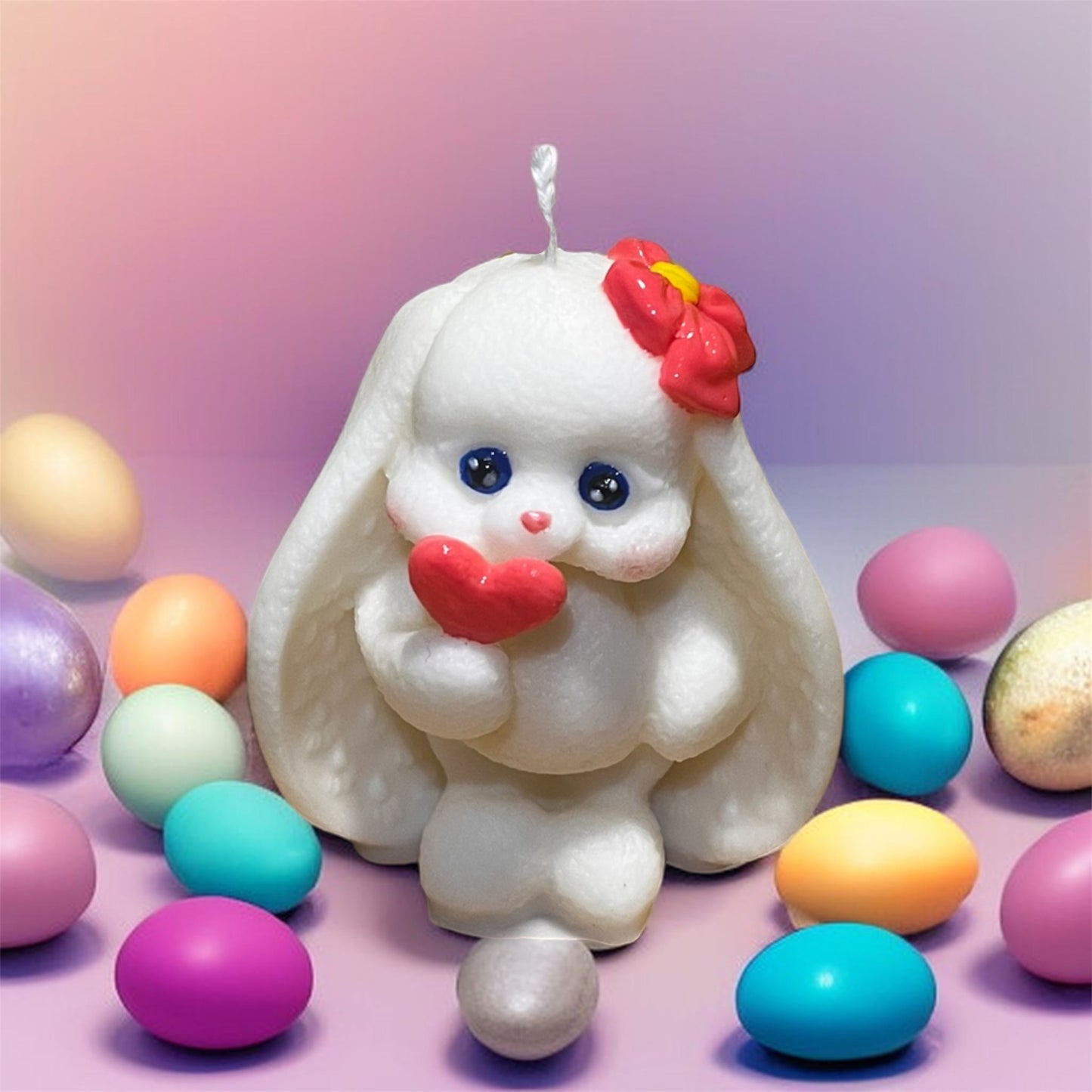 Candela decorativa coniglietta bianca con cuore rosso e uova pasquali colorate.